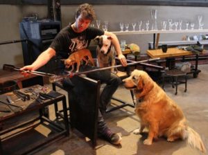 3 dogs surrounding glassblower