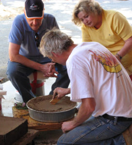 Artist working on mold while two people spectate