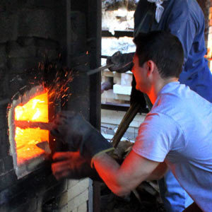 Artist spinning glass pipe into furnace