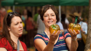 Two Women observe two small orange glass pumpkins