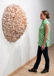 Woman observing Glass Sculpture hanging on wall