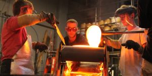 Jocelyne Prince and staff members pouring molten glass into mold