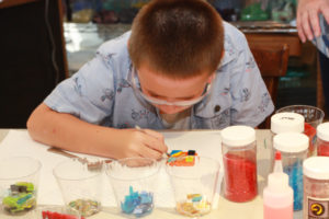 A child works intently on a fused glass magnet