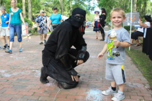 Costumed ninja and child with an ice cream cone posing for a picture during Fantasy Faire at WheatonArts.