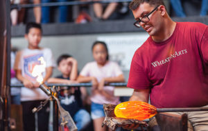 Glass Studio Artist Skitch Manion shaping glass in front of an observant audience