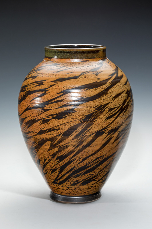 Tan ceramic vase with brown tiger-like stripes. The light creates highlights at the top of the vase. Created by Terry Plasket.