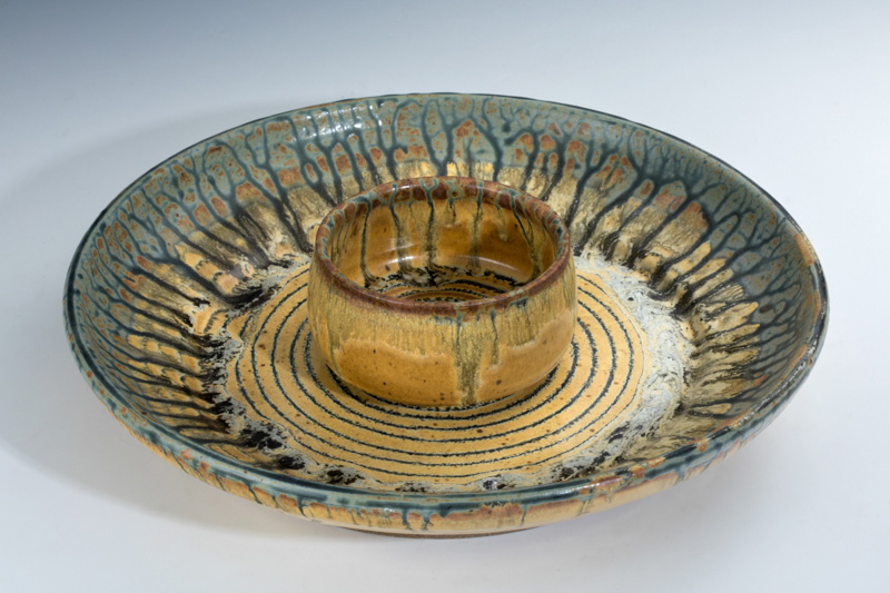 Small tan ceramic bowl with deep blue accents sitting on top of a plate with a matching color scheme. Created by Terry Plasket.