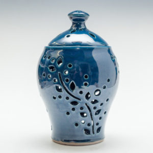 Blue jar with lid, decorated with cut out flowers and small circles. Created by Phyllis Seidner