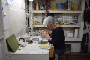 Artist Emily Brown applying enamel to glass cylinder