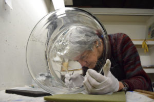 Artist Emily Brown applying enamel to glass cylinder