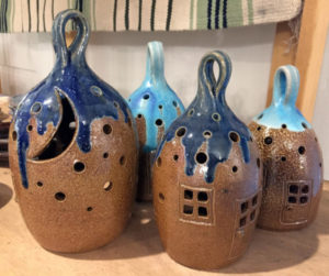 4 brown Ceramic Luminaries shaped like small homes with blue hanging tops.