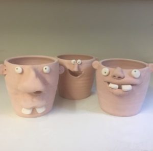 Three unfired ceramic egg separators with funny faces and large white teeth. Created for Tessa Peterzak's Egg Separator class.