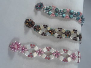 3 flower lattice beaded bracelets in teal and pink, brown and white, and pink and white.