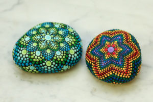 Two rocks with dotted mandalas painted with a rainbow of colors.