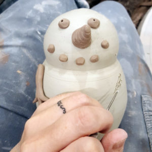 Closeup of a hand sculpting a clay snowman