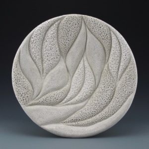 Textured ceramic circle decorated with flowing leaves and tiny holes. Created by Judi Tavill.