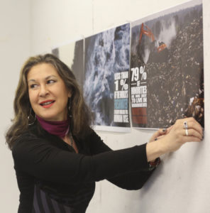 Medium shot of Eve Andrée Laramée pinning a poster to a wall, Symbiotic Spheres exhibiting artist.