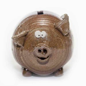 Brown ceramic cartoon pig with tiny eyes, floppy ears, and a smile. Created by Tessa Carlton