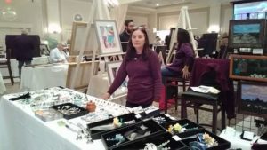 Glass artist Susan Boyce displaying her booth of various works.