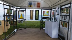 Katherine Cheetham's work in fused and framework glass on display in a booth on a waterfront