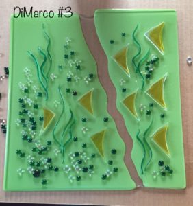 Green glass panel in two segments with green glass seaweed, small marbles, and yellow glass triangles, by Deborah DiMarco