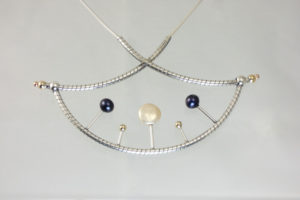 Necklace created by Gina Romano showcasing a pendant of silver tubing decorated with gold, pearl, and iridescent blue spheres