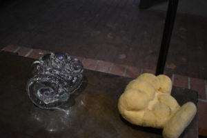 On the right, a large sculpted foam piece resembling a fist. On the left, a matching glass form of the same size and design.