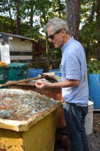 "Emanation 2019" Artist Richard Torchia looks at a fragment of glass from a large pile in a large yellow metal bin.