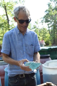 "Emanation 2019" Artist Richard Torchia smiles, looking down at the rock of rough blue glass in his hands.