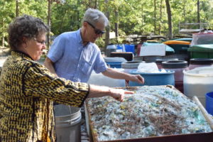 "Emanation 2019" Artist, Richard Torchia and "Emanation 2019" Curator, Julie Courtney sift through fragments of glass and other materials in a large crate.