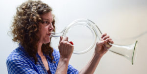 Emanation 2019 Artist Martha McDonald playing a clear glass bugle with a large circle loop