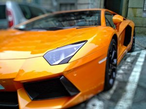 closeup of orange sports car in parking lot