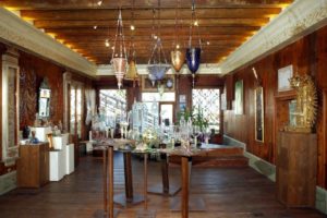 Beautiful room with wooden walls and ceiling, glass artwork displayed in the center of the room on tall, small square wooden tables