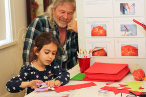 A young child concentrates on creating a paper lantern in the Down Jersey Folklife Center at WheatonArts