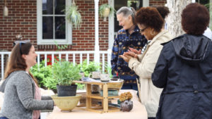 Visitors talk with Amy Peseller and observe her pottery outside of the WheatonArts Pottery Studio