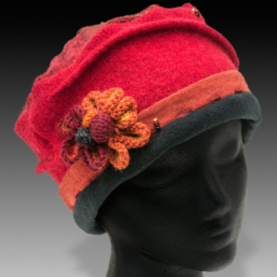 A red wool hat with a knitted flower embellishment and a black band around the bottom