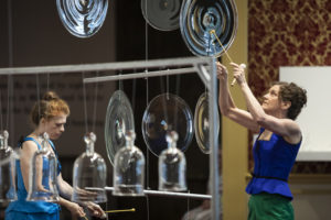 Martha McDonald and Laura Baird play the glass cloches and rondels with small wooden mallets for "Phantom Frequencies" at the Museum of American Glass