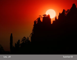 Photograph by Michael Leu of a rich red sunrise rising behind the silhouettes of tall rocks and trees, text in a gray bar across the bottom that says Leu 01 and Sunrise 03