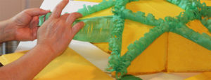 Closeup of hands carefully working on a Philippine Parol, a yellow star lantern with green accents