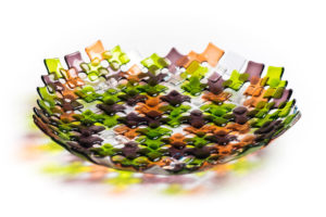 Green, purple, orange, and white bowl by Stephanie Baness formed with small overlapping glass squares of each color