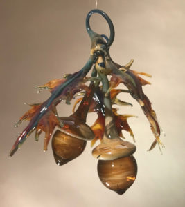 Hanging flamework sculpture by Stephen Brucker of orange oak leaves surrounding two large acorns