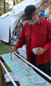 Artist carefully places paint down to marble a silk scarf during the Festival of Fine Craft