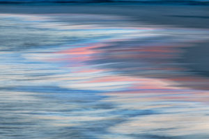 Photograph by Frederick Ballet of waves closeup with white and pink reflections on the water.