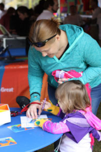 An adult assists a child using a stencil to color during HalloWheaton