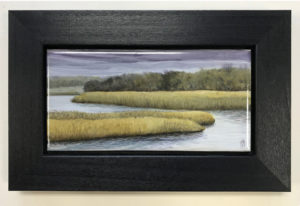 A painted piece of porcelain in a thick black frame showcasing a scene of a river winding through the marsh. Created by Michelle Post.