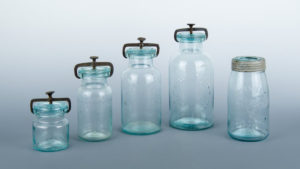 Five transparent blue jars of varying heights.