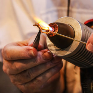 Closeup of an artist's hands flameworking with a torch.