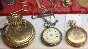 A collection of three pocketwatches in different sizes laying on a table.