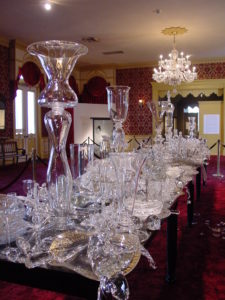 Crowded table of clear glass objects by Beth Lipman, "Bancketje (Banquet)," 2003, glass, oak, oil and mixed media, created at WheatonArts, in the collection of the Smithsonian American Art Museum.