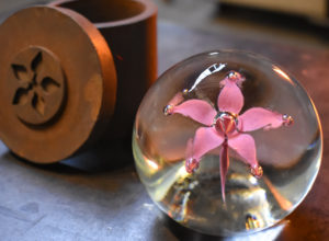 A pink five petal rose paperweight with bubbles on the end of each petal and a larger one at the center of the flower.